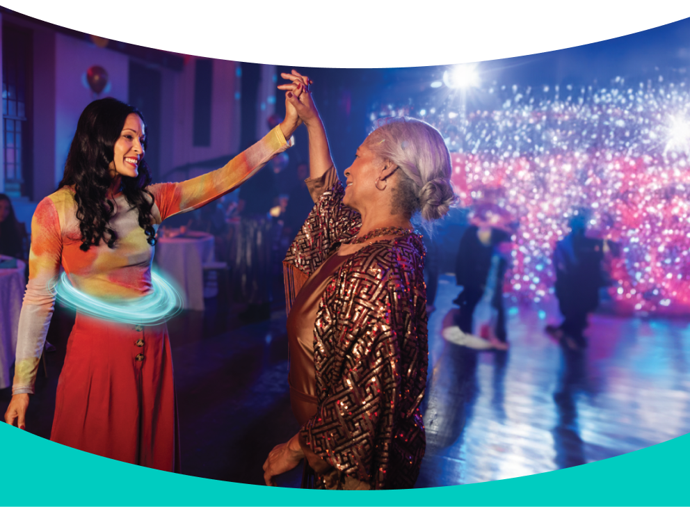 Two adult women smiling at each other and dancing at a party