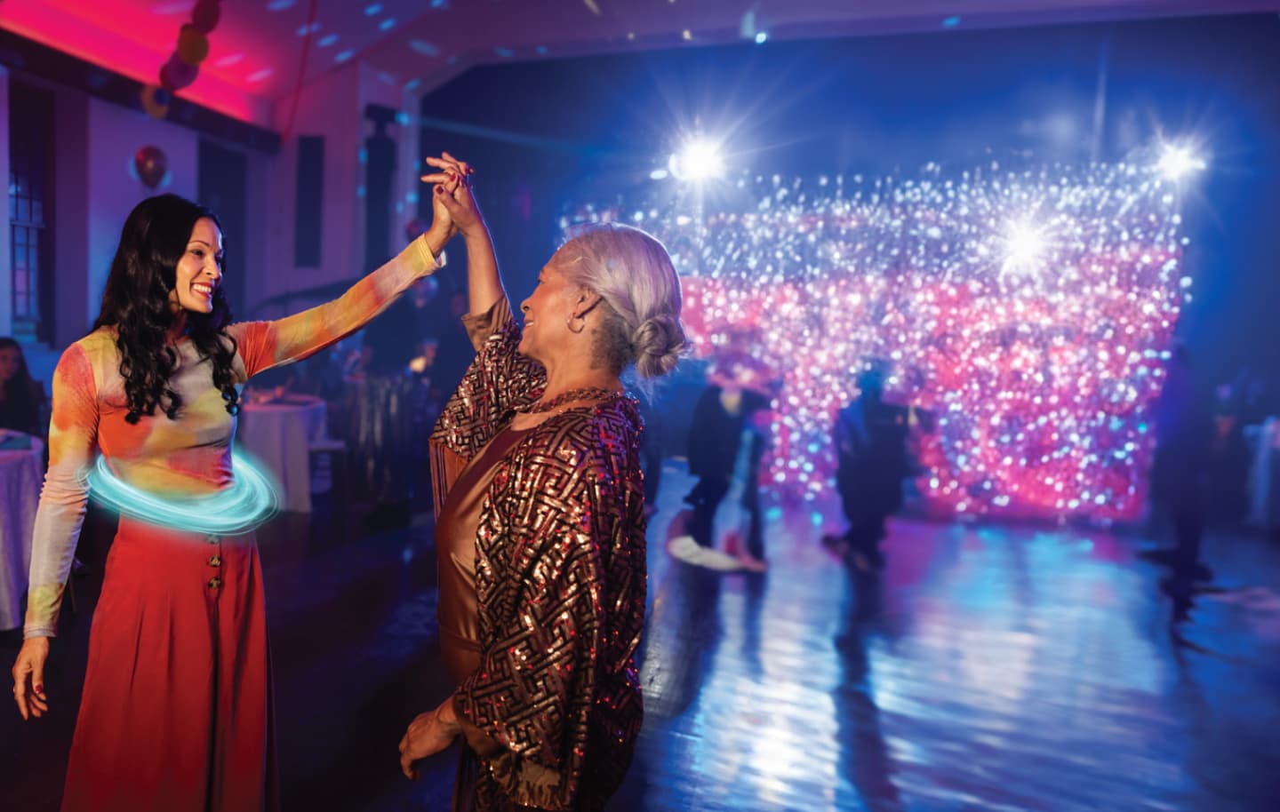 Two adult women smiling at each other and dancing at a party