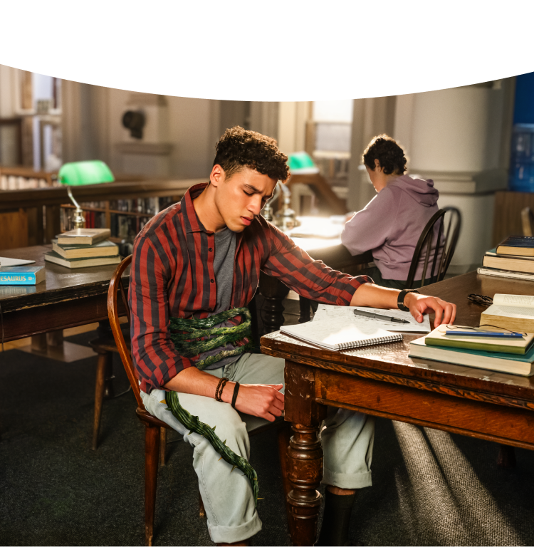 Adult male student sitting in discomfort at the library with a green vine wrapped around his stomach