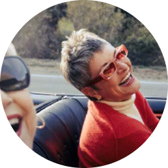 Woman in red sweater and sunglasses laughing in a car