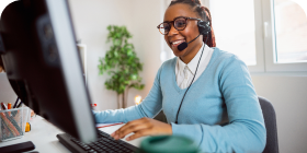 Woman in blue sweater smiling while talking into a headset