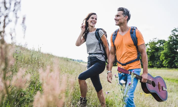 Man with guitar hiking with woman