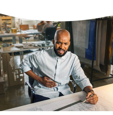 Man sitting at desk holding his stomach in discomfort