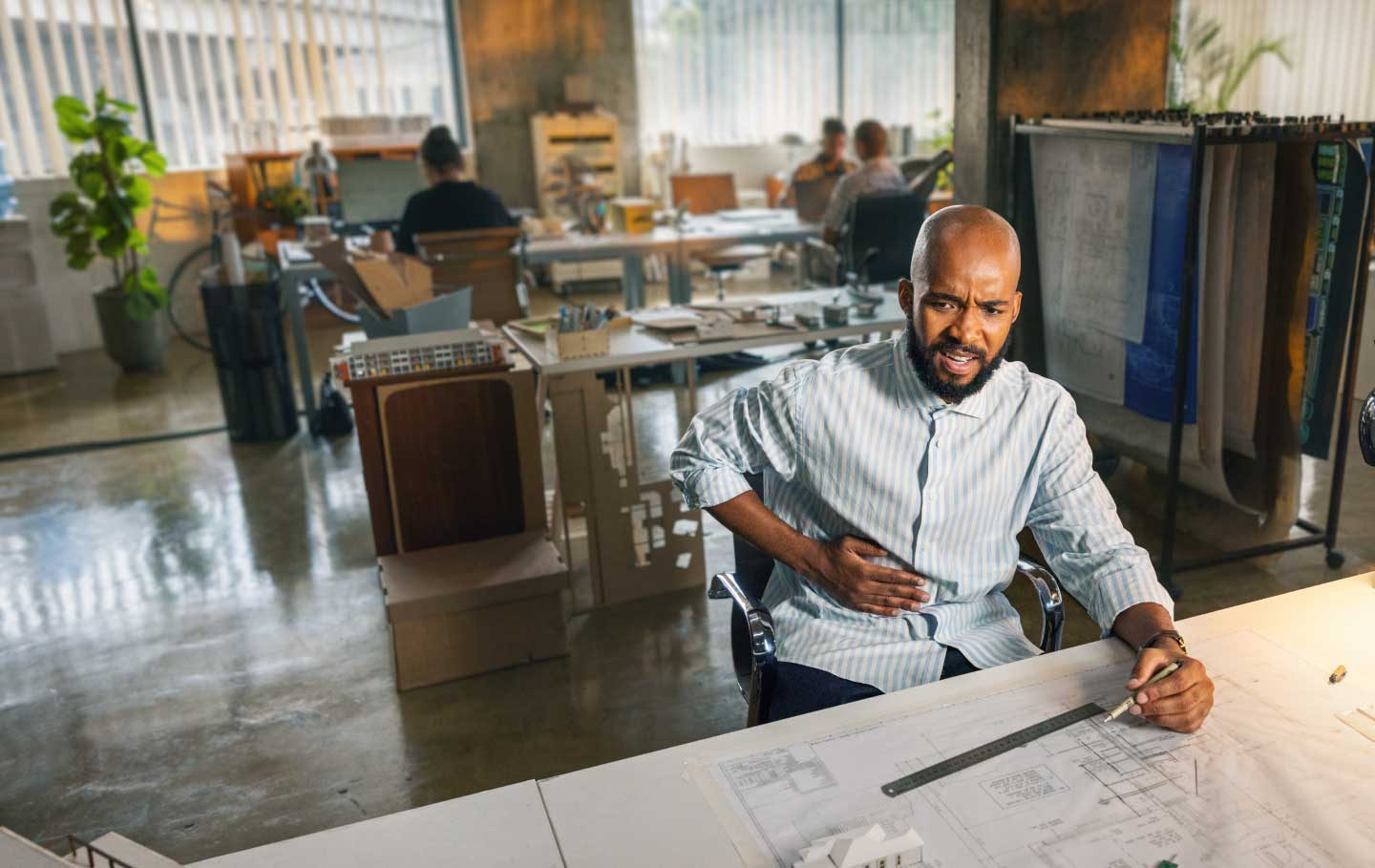 Man sitting at desk holding his stomach in discomfort