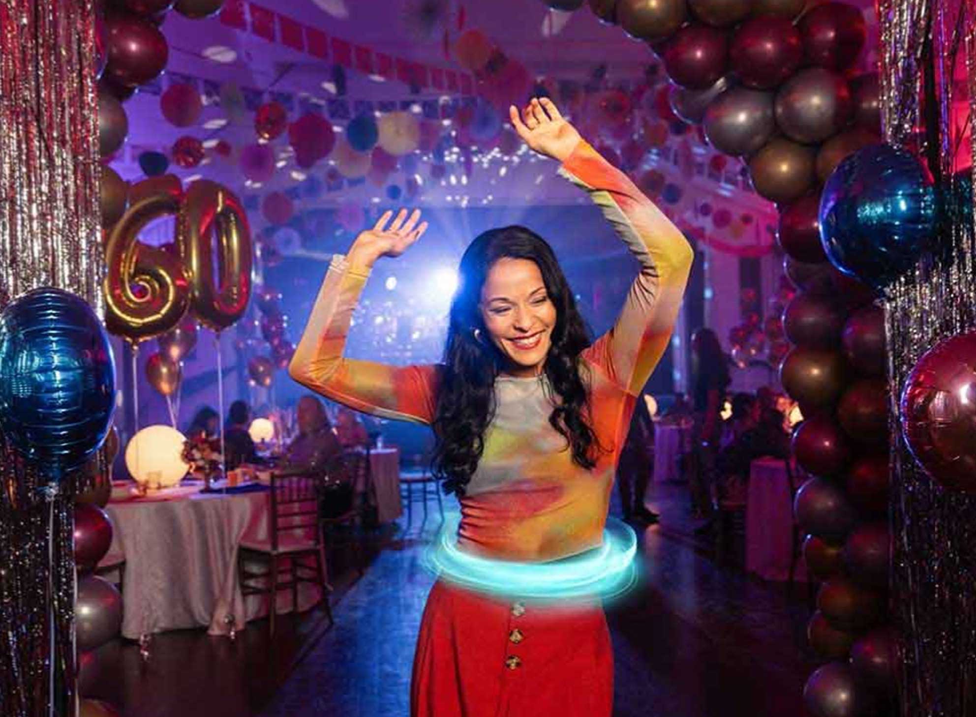 Paciente femenina con colitis ulcerosa (CU) tratada con TREMFYA®, bailando y divirtiéndose en su fiesta de cumpleaños número 60.